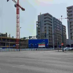 Budowa nowych bloków mieszkalnych w Krakowie. W tle widać nowoczesne budynki, a na pierwszym planie plac budowy z dźwigiem. To miejsce, gdzie w ciągu 10 lat ceny mieszkań kraków wykres mogą znacząco wzrosnąć.