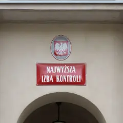 Tablica z napisem "Najwyższa Izba Kontroli" i godłem Polski na jasnym budynku.