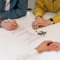 Podpisanie umowy rezerwacyjnej nieruchomości. Klucze i dokumenty na stole.