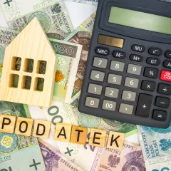 Drewniany domek, banknoty i kalkulator sugerują, ile wynosi podatek od nieruchomości.