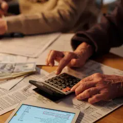 Dwie osoby liczą pieniądze i dokumenty, próbując zrozumieć, jaki jest podatek od spadku.