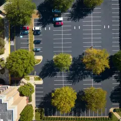 Widok z lotu ptaka na parking przy blokach mieszkalnych. Zastanawiasz się, ile miejsc parkingowych na mieszkanie jest dostępne?