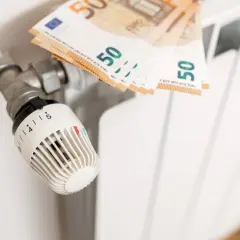 Termostat grzejnikowy i banknoty 50 euro. Obrazek ilustruje, jak spółdzielnia rozlicza ogrzewanie, pokazując koszty związane z ciepłem.