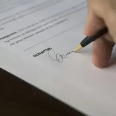 Dłoń podpisuje dokument, przedłużenie umowy najmu na kolejny rok.