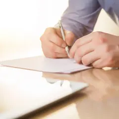 Mężczyzna pisze piórem na kartce papieru. To może być list mazalny, który jest ważnym dokumentem.