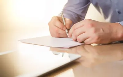 Mężczyzna pisze piórem na kartce papieru. To może być list mazalny, który jest ważnym dokumentem.