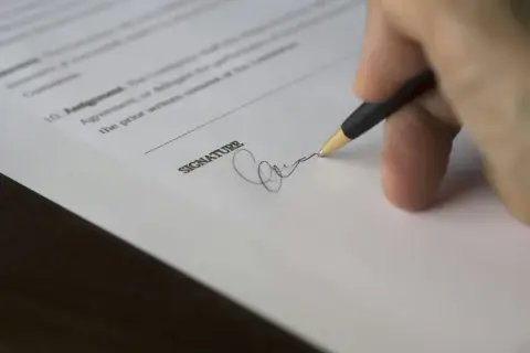 Dłoń podpisuje dokument, przedłużenie umowy najmu na kolejny rok.
