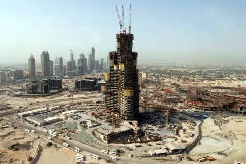 Budowa Burj Khalifa w Dubaju, widok z lotu ptaka na plac budowy, dźwigi i inne wieżowce w tle.