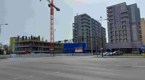 Budowa nowych bloków mieszkalnych w Krakowie. W tle widać nowoczesne budynki, a na pierwszym planie plac budowy z dźwigiem. To miejsce, gdzie w ciągu 10 lat ceny mieszkań kraków wykres mogą znacząco wzrosnąć.