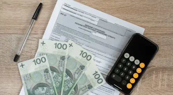 Formularz PIT-37, banknoty 100 zł, długopis i kalkulator na telefonie. Czy wpisowe jest zwrotne?