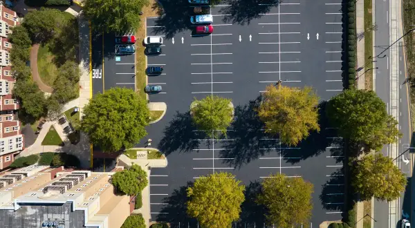 Widok z lotu ptaka na parking przy blokach mieszkalnych. Zastanawiasz się, ile miejsc parkingowych na mieszkanie jest dostępne?