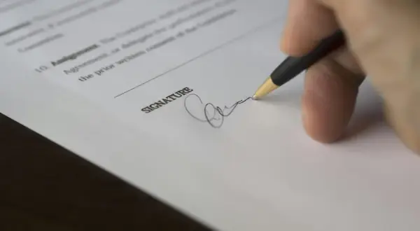 Dłoń podpisuje dokument, przedłużenie umowy najmu na kolejny rok.