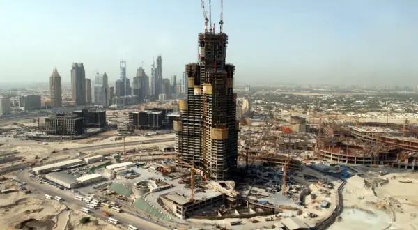 Budowa Burj Khalifa w Dubaju, widok z lotu ptaka na plac budowy, dźwigi i inne wieżowce w tle.