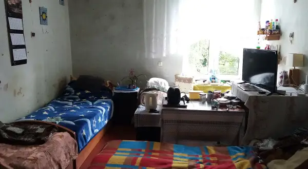 Pokój z dwoma łóżkami, telewizorem i oknem. Czy bezdomny może starać się o mieszkanie? Tak, istnieją programy pomocowe.