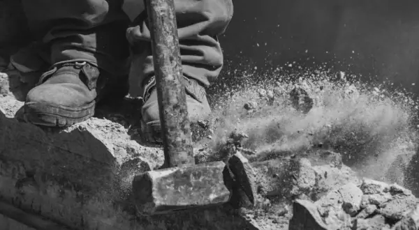 Młot rozbija beton, tworząc chmurę pyłu. To może być kara za wyburzenie ściany nośnej.
