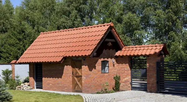 Nowy budynek gospodarczy z cegły i czerwonym dachem. Zastanawiasz się, ile kosztuje przekształcenie budynku gospodarczego na mieszkalny?