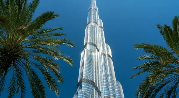 Burj Khalifa, najwyższy budynek świata, ma 163 piętra. Widok z dołu, z palmami w kadrze.