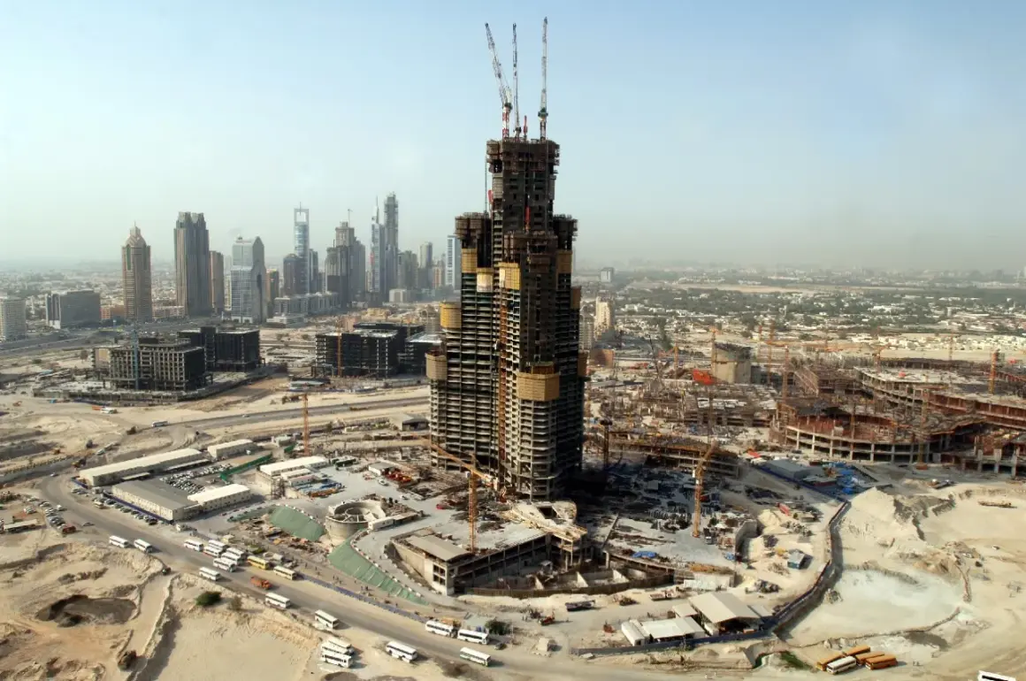 Budowa Burj Khalifa w Dubaju, widok z lotu ptaka na plac budowy, dźwigi i inne wieżowce w tle.