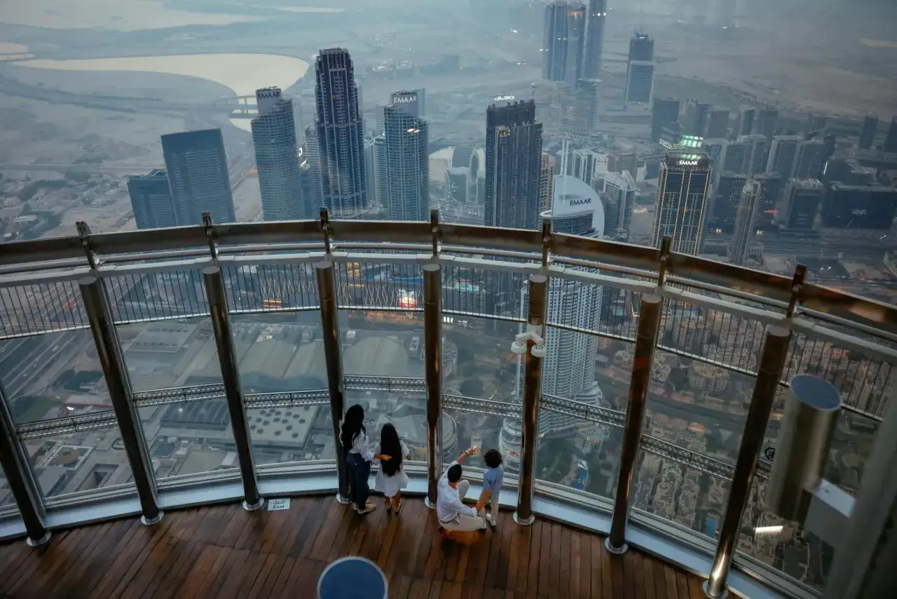 Rodzina podziwia panoramę Dubaju z tarasu widokowego. W oddali widać drapacze chmur, a wśród nich najwyższy budynek na świecie.