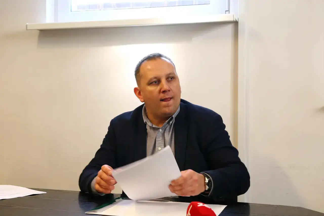 Mężczyzna w garniturze przegląda dokumenty, dyskutując o tym, ile zarabia członek zarządu spółdzielni mieszkaniowej.