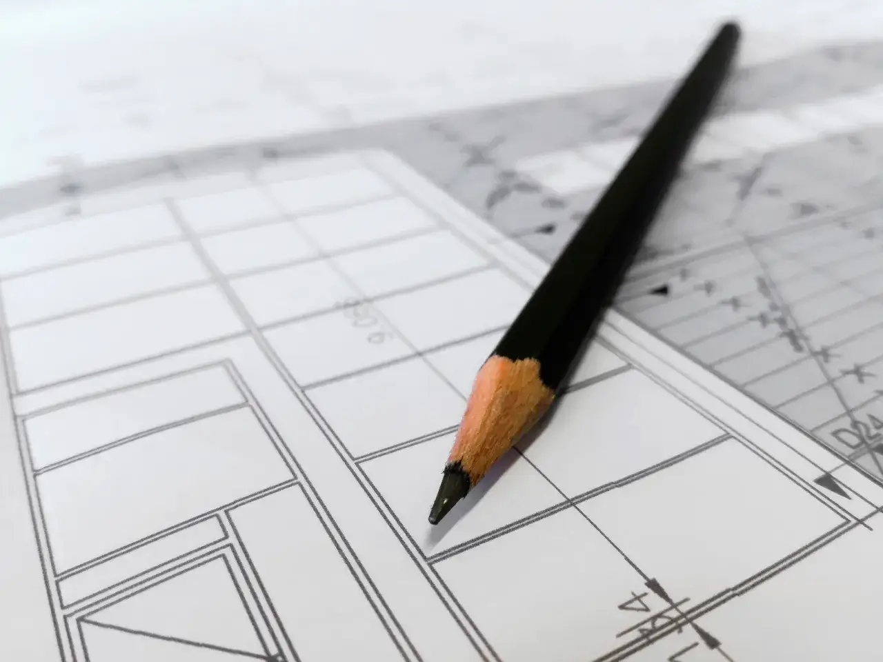 Ołówek na papierze z planem. Dowiedz się, jak uzyskać mapę zasadniczą, analizując szczegóły rysunku technicznego.