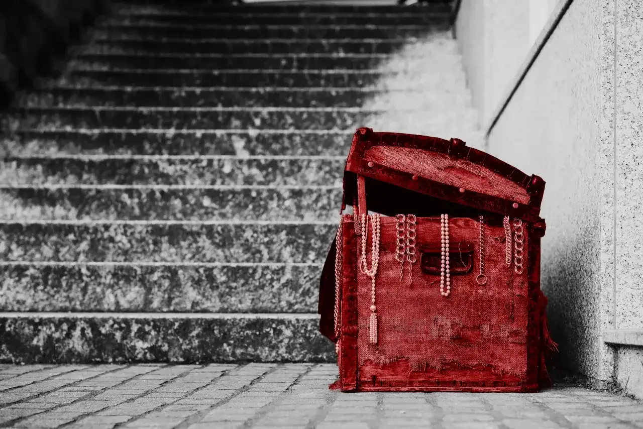 Czerwona skrzynia z biżuterią na schodach. Czy od spadku po rodzicach płaci się podatek?
