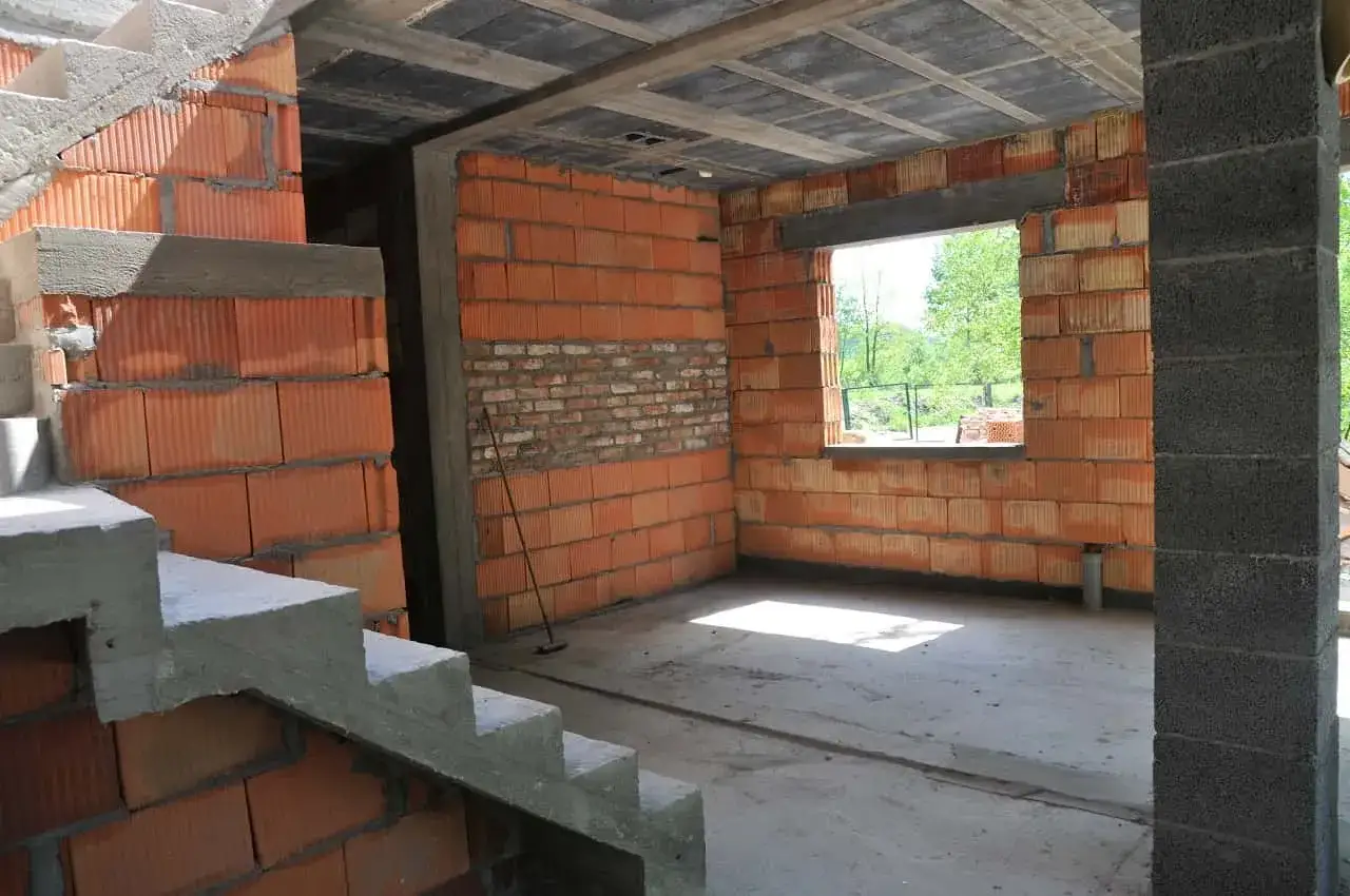 Budynek w budowie, schody betonowe, ściany z pustaków ceramicznych. Zastanawiasz się, ile kosztuje przekształcenie budynku gospodarczego na mieszkalny?