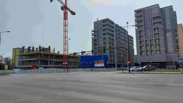 Budowa nowych bloków mieszkalnych w Krakowie. W tle widać nowoczesne budynki, a na pierwszym planie plac budowy z dźwigiem. To miejsce, gdzie w ciągu 10 lat ceny mieszkań kraków wykres mogą znacząco wzrosnąć.
