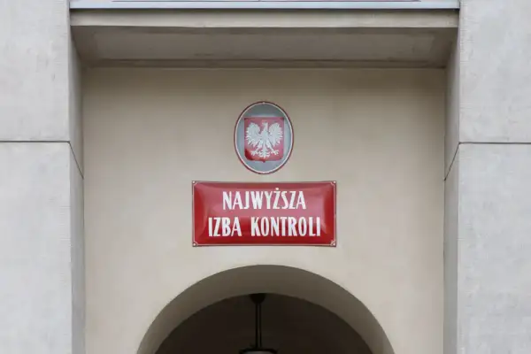 Tablica z napisem "Najwyższa Izba Kontroli" i godłem Polski na jasnym budynku.