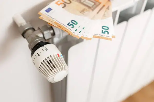 Termostat grzejnikowy i banknoty 50 euro. Obrazek ilustruje, jak spółdzielnia rozlicza ogrzewanie, pokazując koszty związane z ciepłem.